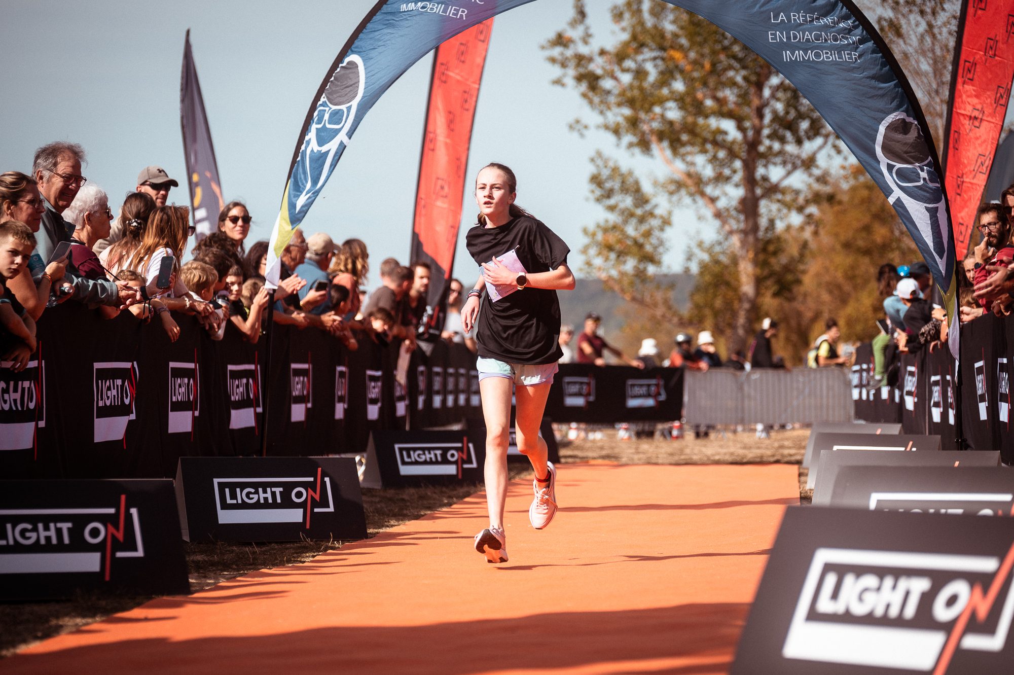 Arrivée d'une jeune triathlète sous l'arche LIGHT ON, devant le public