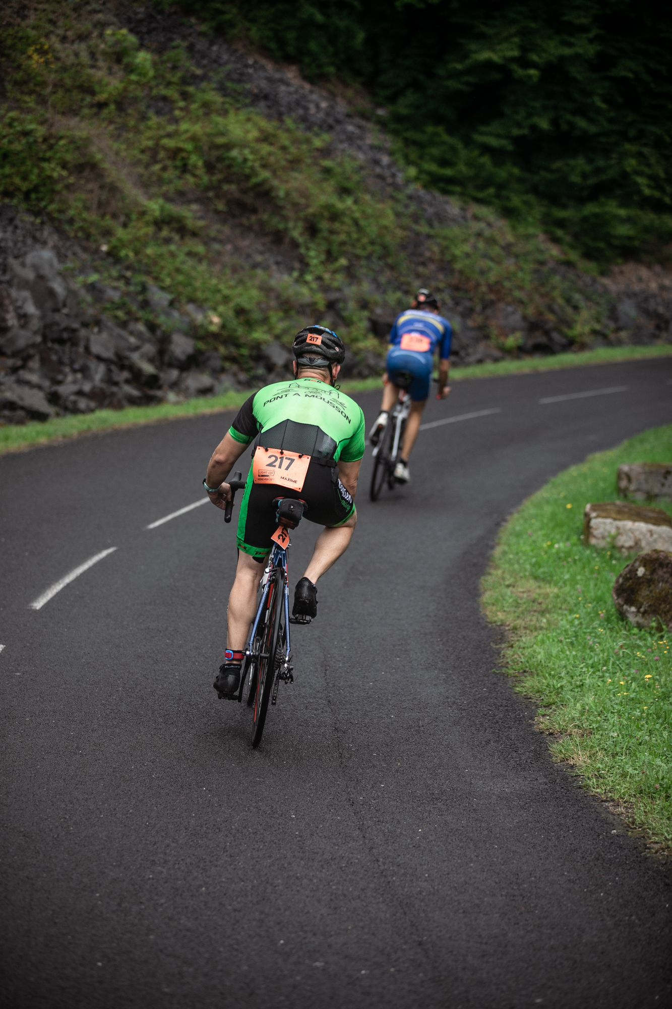 Deux triathlètes à vélo dans un virage, le lac de Pierre-Percée en contrebas